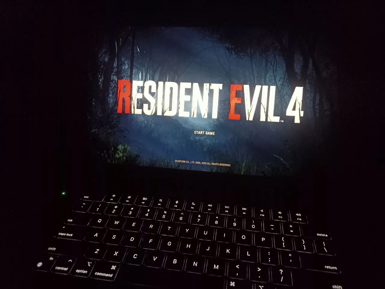 Resident Evil 4 title screen on a laptop in a dark room